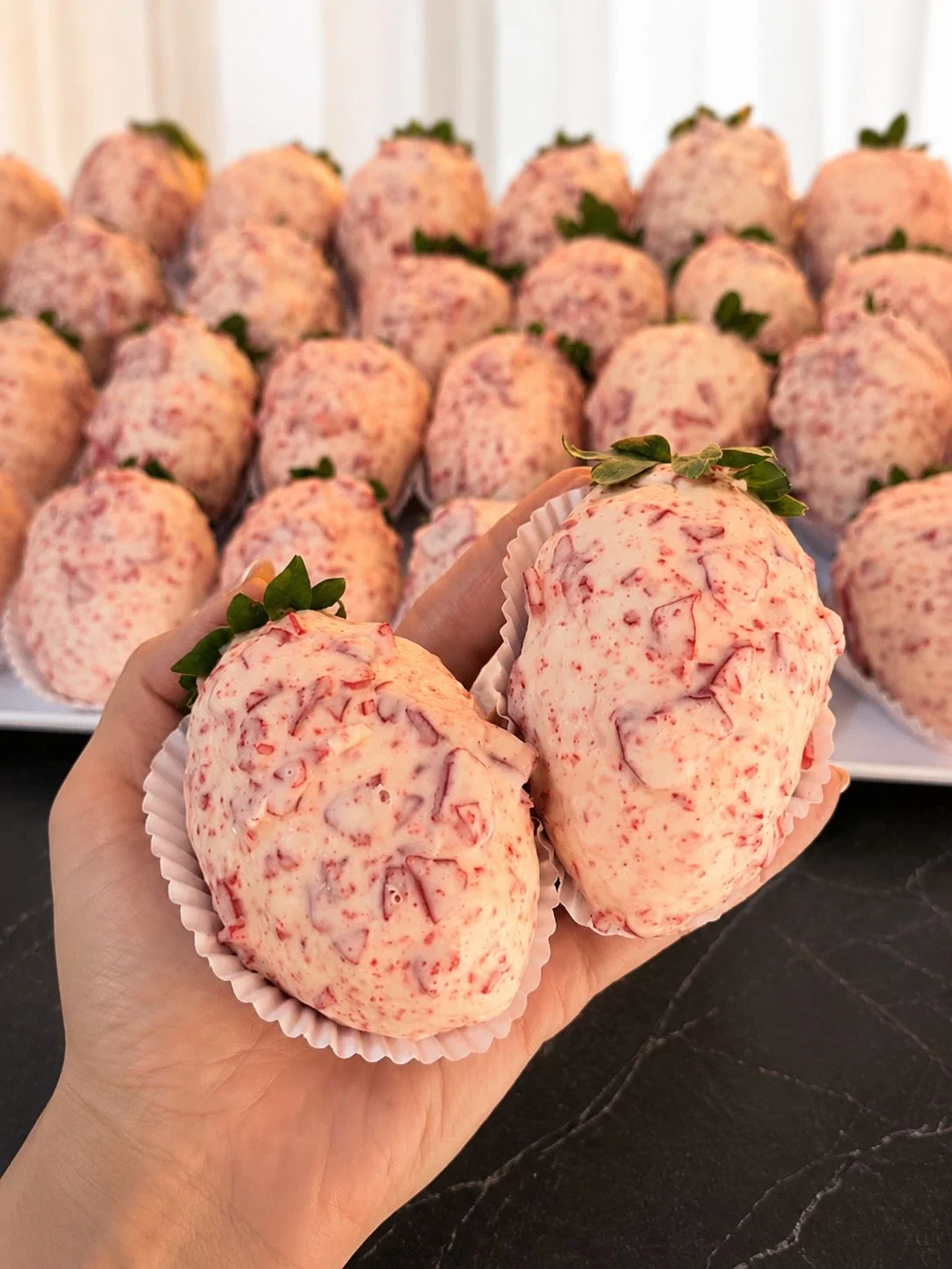 Vários Morangos Cravejados produzidos, dois deles segurados na mão